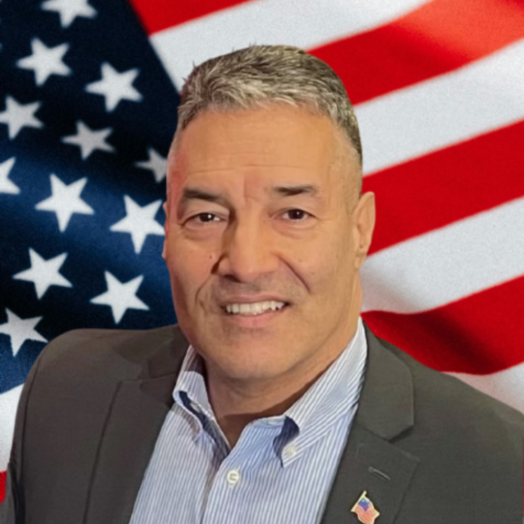 JR Rodriguez smiles in front of an American flag