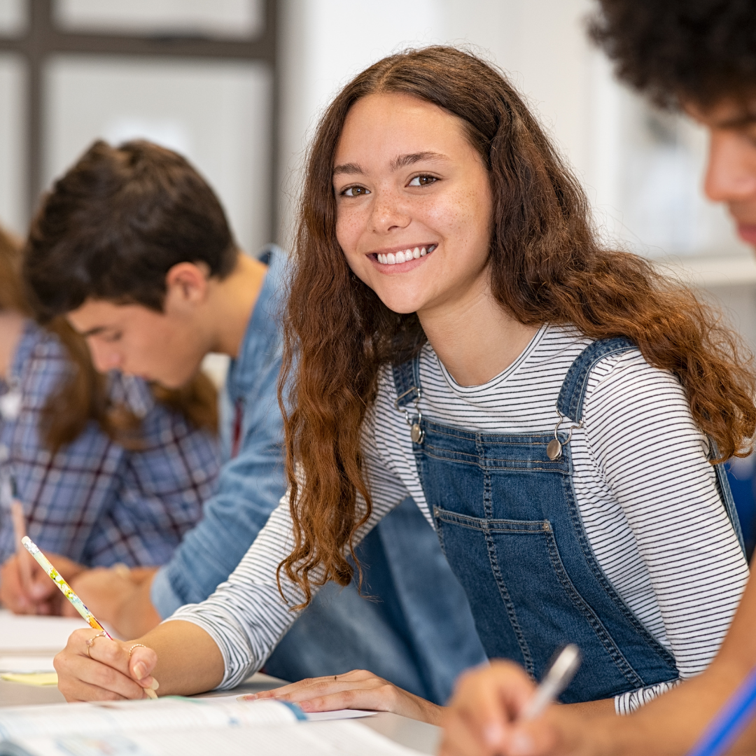 A student smiles for the camera as she studies with a group.