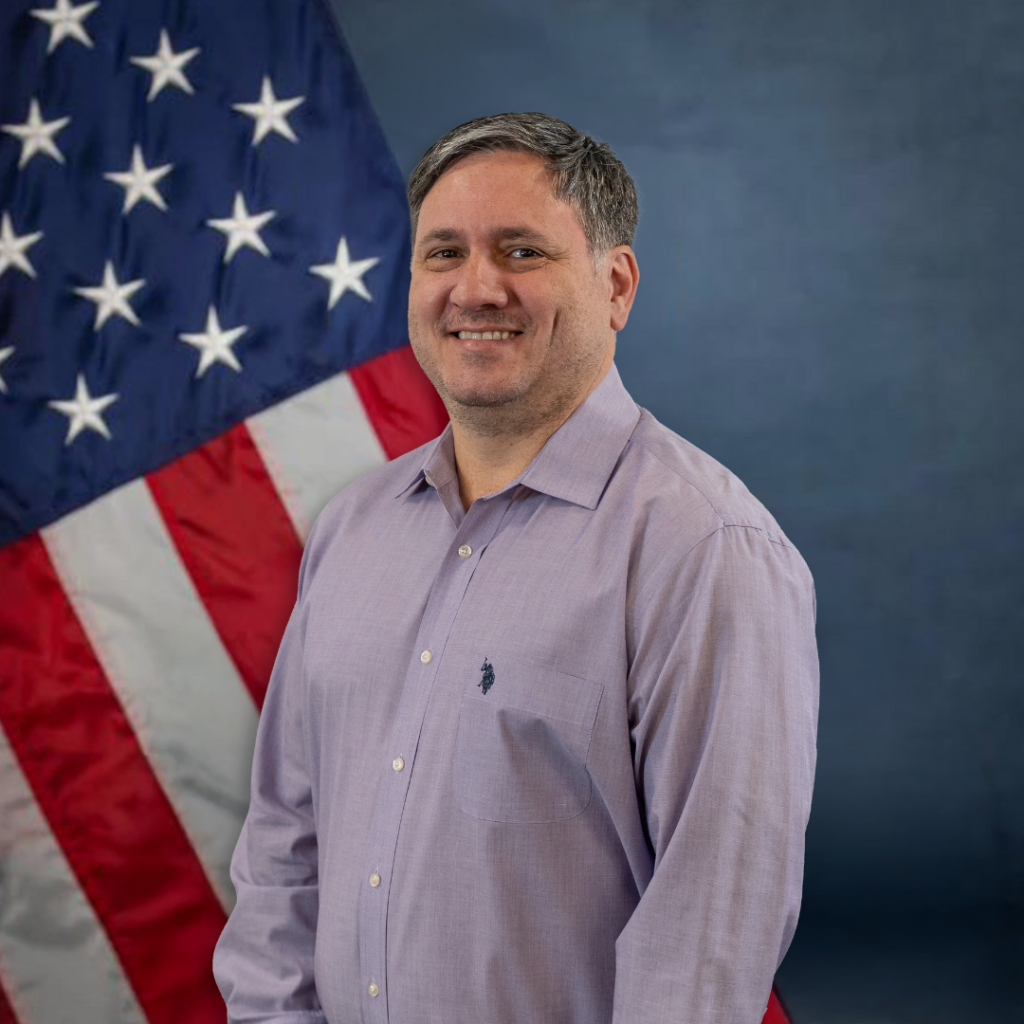 Derreck Martell smiles in front of an American flag