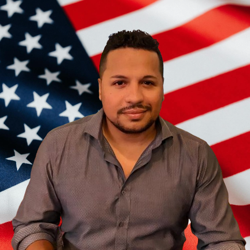 Oscar Escobar smiles in front of an American flag